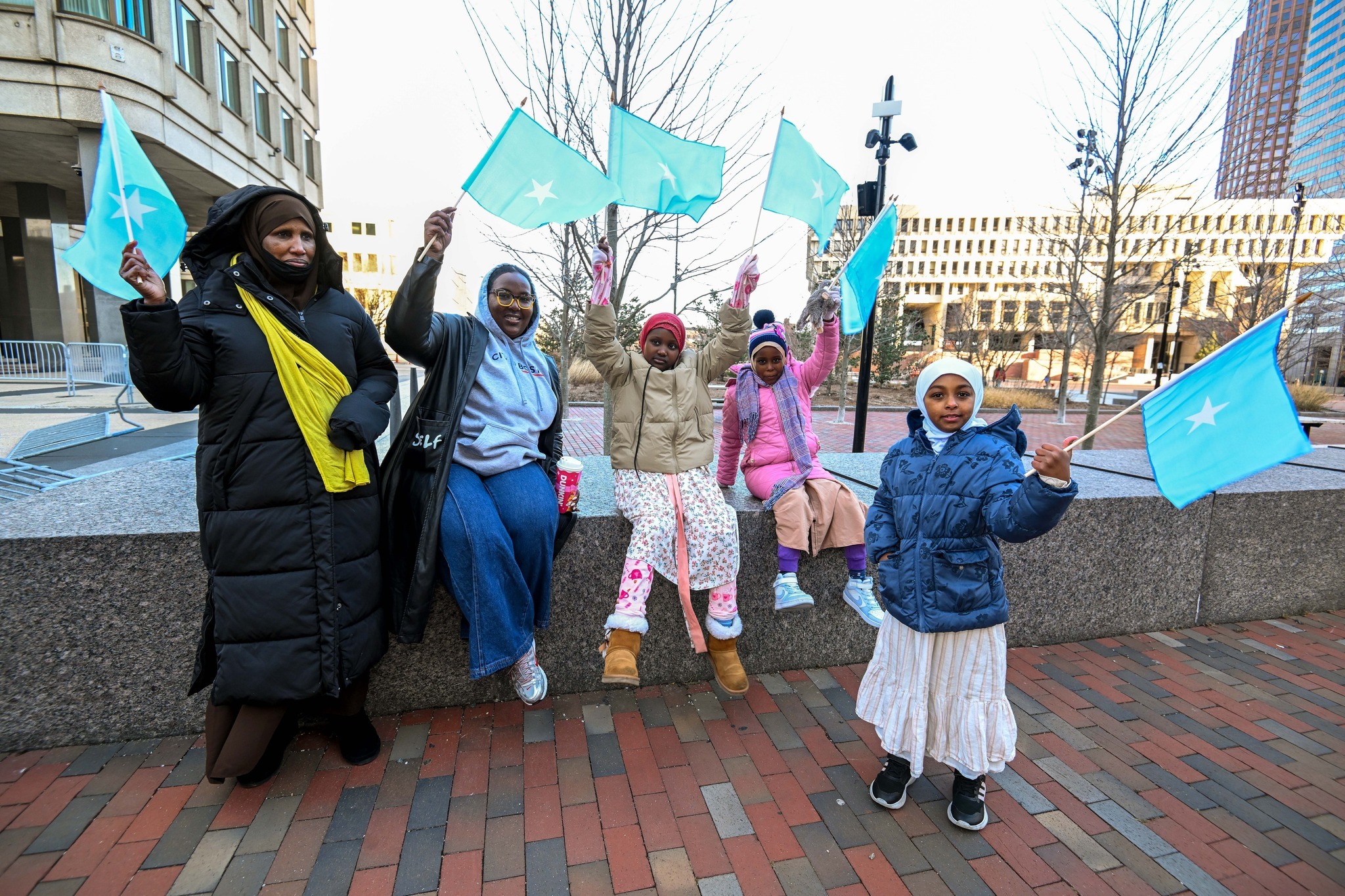 In Boston, a Somali mother and her children wave the Somali flag together during a community gathering.