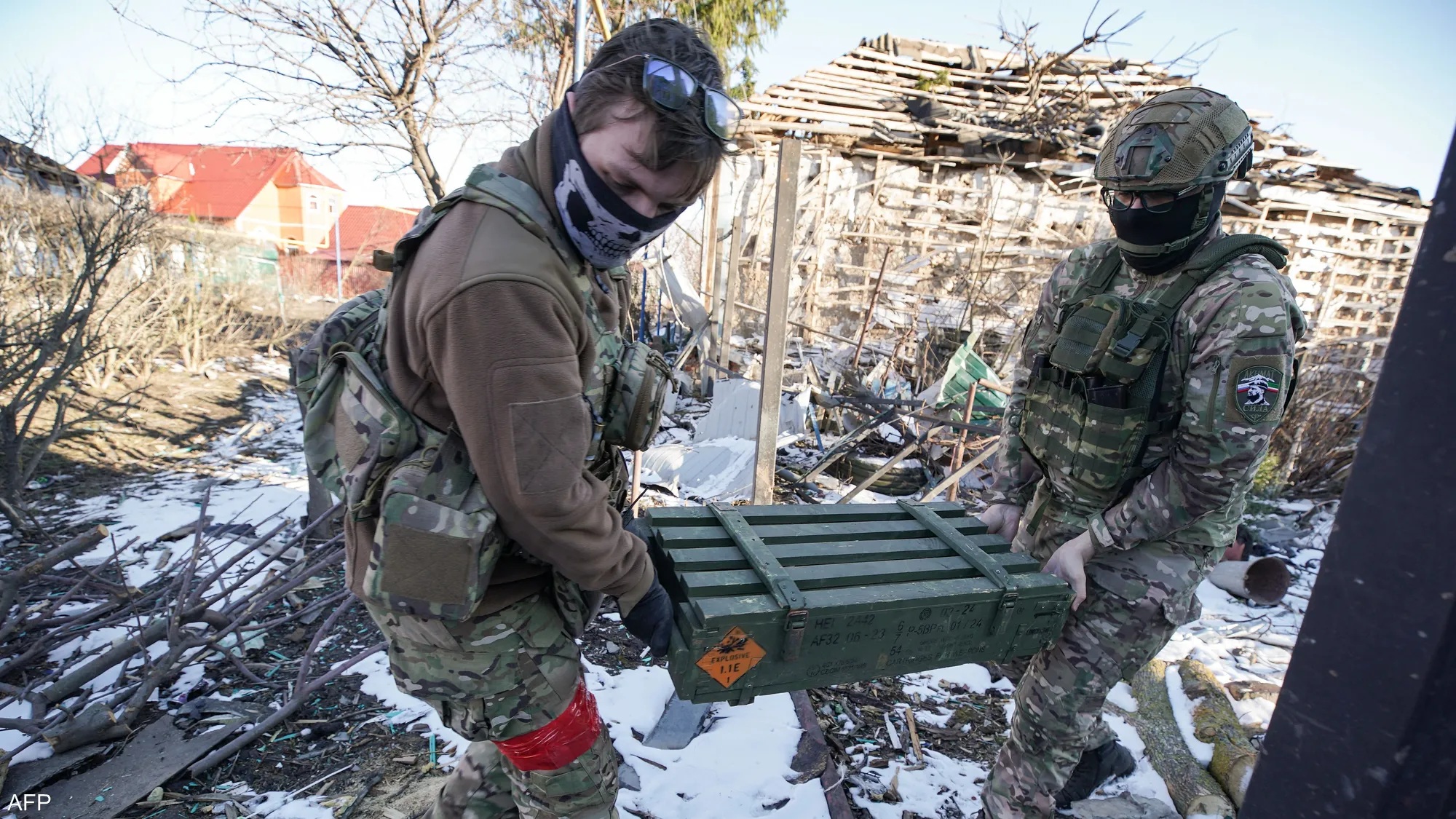 Two Russian soldiers carry and load ammunition at an active frontline during ongoing combat operations.