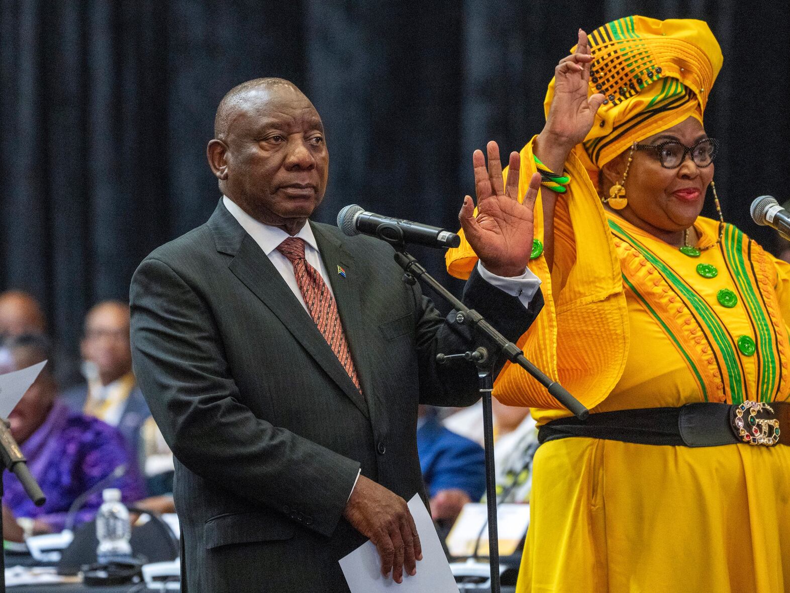 South African President Cyril Ramaphosa raises his hand as he is sworn is as a member of Parliament ahead of an expected vote by lawmakers to decide if he is reelected as leader of the country in Cape Town, South Africa, Friday. At right is Pemmy Majodina, a lawmaker with his African National Congress party.  Jerome Delay / AP