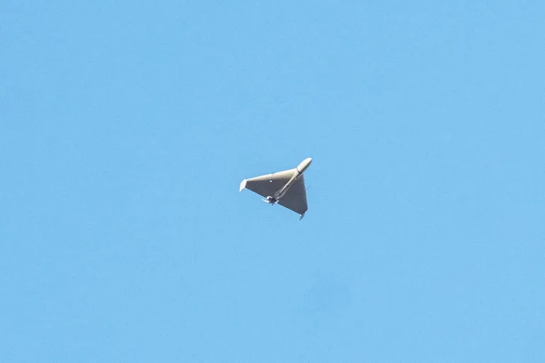 A Russian attack drone is shown in flight during daylight hours, captured against a clear sky.