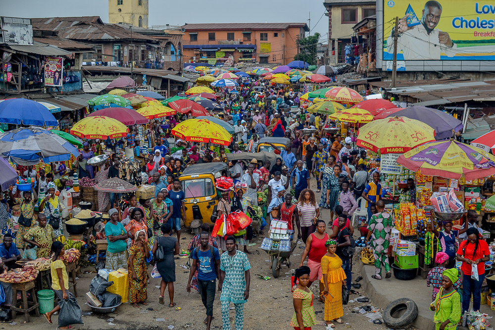 Traders and customers navigate busy market stalls in Nigeria, where easing inflation has yet to significantly reduce the high cost of everyday food and essential goods.