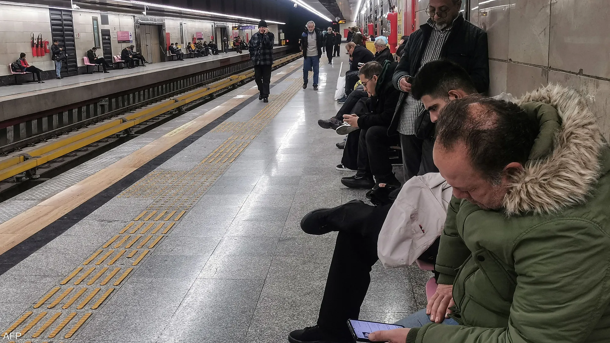 Commuters wait at a Tehran train station after services were suspended following an Israeli military warning to avoid trains and railway lines amid escalating tensions.