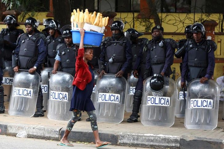 A woman walks past police officers as Angola's election commission says ruling MPLA party leads with 52% majority, after the general election close in Luanda, Angola August 25, 2022. REUTERS/Siphiwe Sibeko