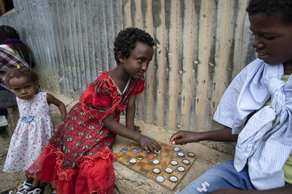 Elena, 7, left, plays a game of checkers using soda bottle tops with friend Hailemariam, 12, at a reception and day center for displaced Tigrayans in Mekele, in the Tigray region of northern Ethiopia, Sunday, May 9, 2021. The Tigray conflict has displaced more than 1 million people, the International Organization for Migration reported in April, and the numbers continue to rise. Some thousands of Eritrean refugees are among the most vulnerable groups in the Tigray conflict and are increasingly caught in the middle of the conflict in Ethiopia's Tigray region. (AP Photo/Ben Curtis)