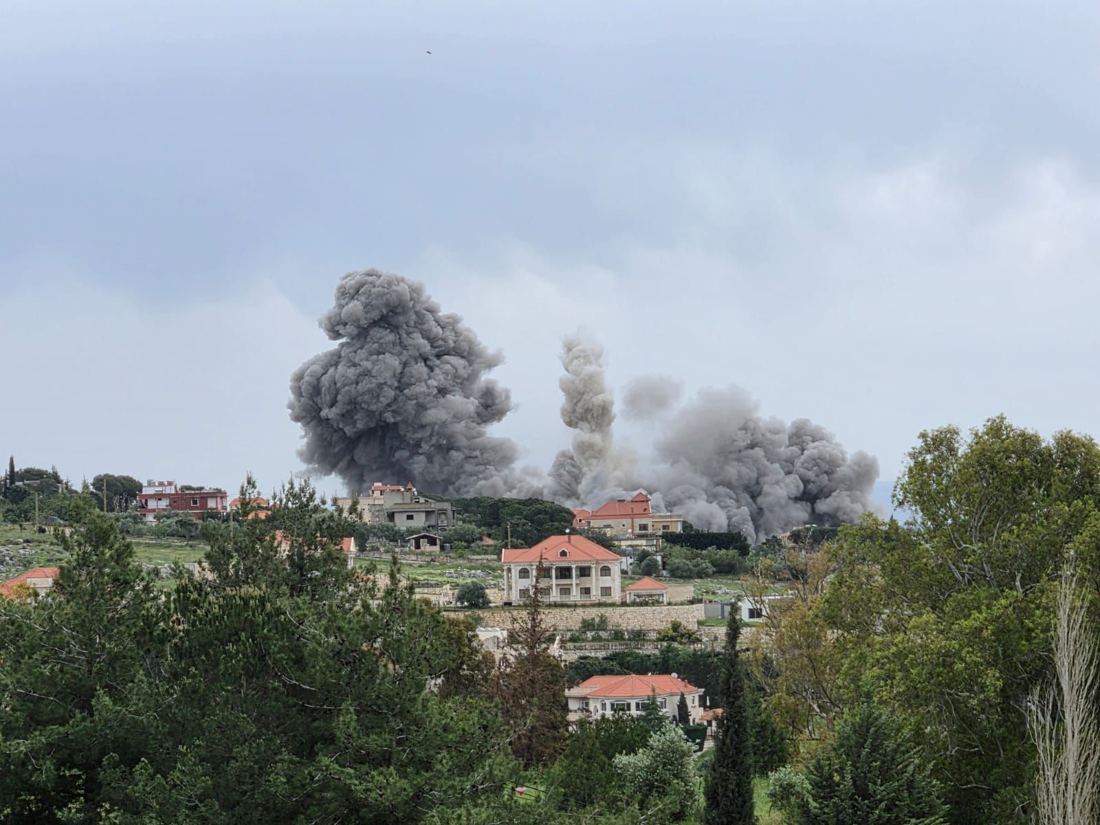 Smoke rises over damaged buildings in southern Lebanon following Israeli airstrikes, with widespread destruction reported.