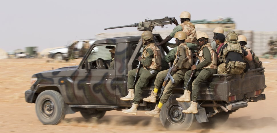 Burkinabe soldiers holding AK-47 rifles during a military patrol in an operation against armed insurgent groups.