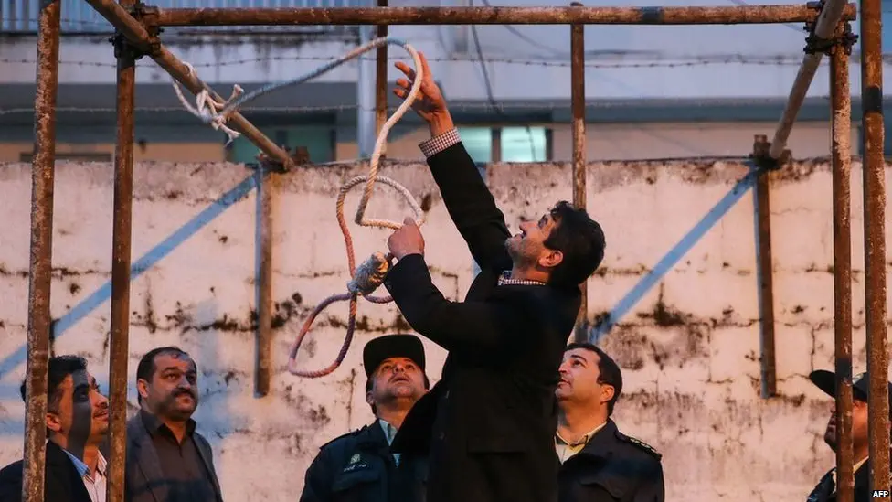 An Iranian official adjusts a noose at a gallows during preparations for an execution, as security personnel observe at a detention facility in Tehran.