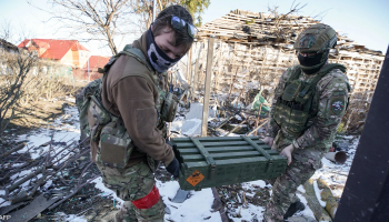 Two Russian soldiers transport ammunition on one of the front-line sectors in Ukraine, in a scene reflecting ongoing logistical support for active combat operations on the battlefield.