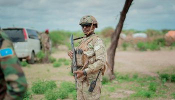 A Somali National Army soldier holding an AK-47 rifle during a field operation, standing alert in a secured area as part of ongoing counterterrorism efforts in southern Somalia.