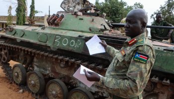 Left: Major General Lul Ruai Koang the spokesperson for the South Sudan People's Defence Forces (SSPDF) shows journalists a captured BMP-2 infantry fighting vehicle nicknamed 