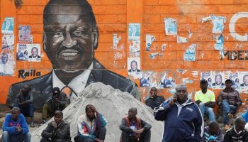 People sit next to a wall mural of Raila Odinga the presidential candidate for Azimio la Umoja and One Kenya Alliance, after the general election conducted by the Independent Electoral and Boundaries Commission (IEBC) in Kibera slums of Nairobi, Kenya August 12, 2022. REUTERS/Monicah Mwangi