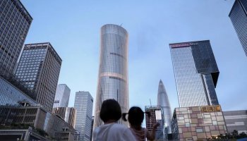 FILE PHOTO: A woman holds a child near office buildings in Shenzhen, Guangdong province, China September 15, 2025. REUTERS/Tingshu Wang/File Photo