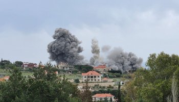 Smoke rises over damaged buildings in southern Lebanon following Israeli airstrikes, with widespread destruction reported.