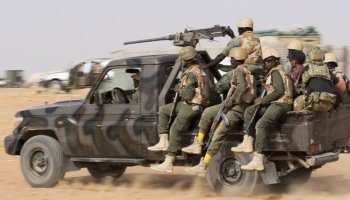 Burkinabe soldiers holding AK-47 rifles during a military patrol in an operation against armed insurgent groups.