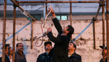 An Iranian official adjusts a noose at a gallows during preparations for an execution, as security personnel observe at a detention facility in Tehran.