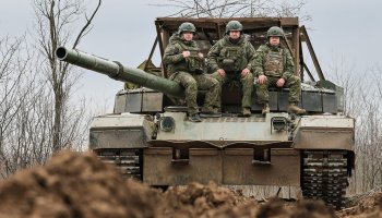 Three Russian soldiers ride atop a tank during operations in Luhansk, eastern Ukraine, as military activity continues in the region.